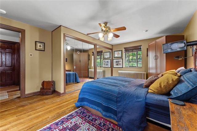 bedroom featuring radiator, baseboards, light wood-type flooring, and ceiling fan