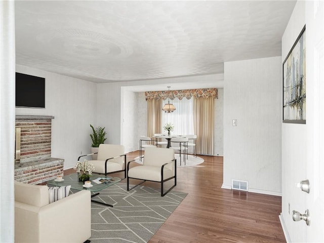 sitting room with wood finished floors, visible vents, and baseboards