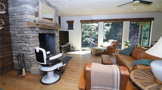 living area with a stone fireplace, hardwood / wood-style flooring, recessed lighting, and a ceiling fan