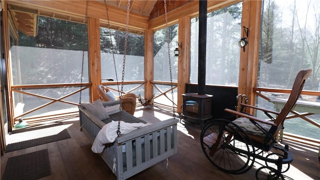 sunroom with a wood stove and vaulted ceiling