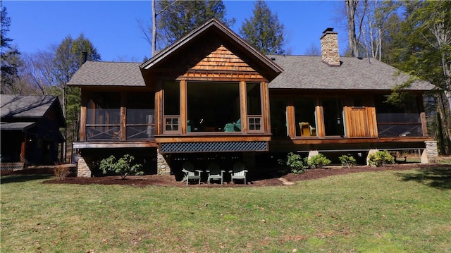 back of property with a lawn, a chimney, roof with shingles, and a sunroom