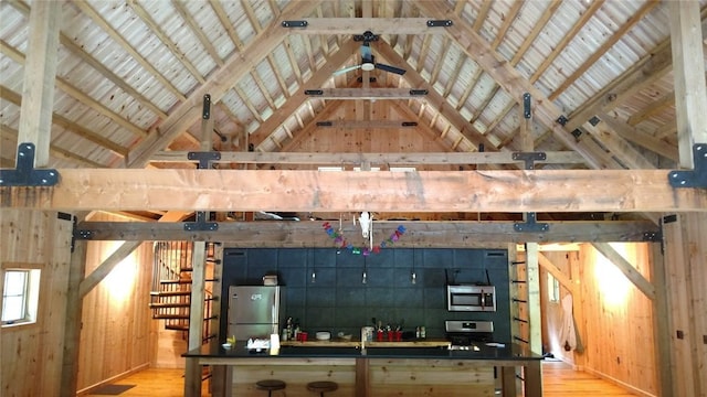 interior space with vaulted ceiling, wood finished floors, wood walls, and stainless steel appliances