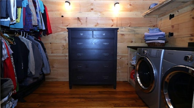 washroom with wood finished floors, washing machine and dryer, laundry area, and wood walls