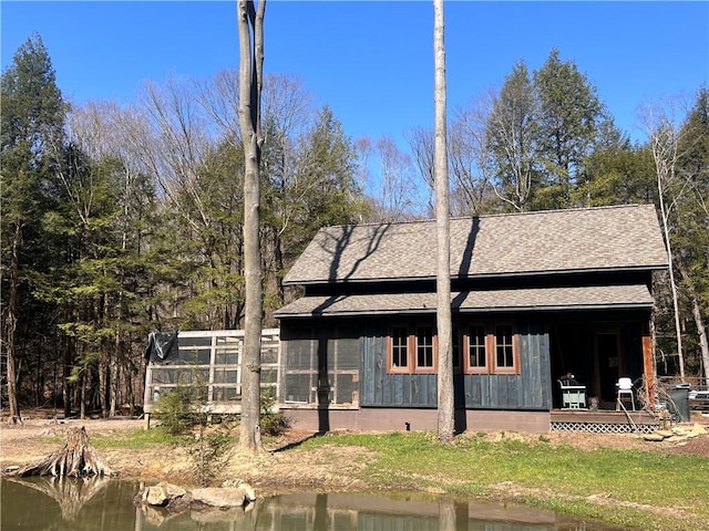 view of home's exterior with a water view and roof with shingles