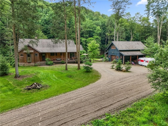 000 Wonder Ln, Punxsutawney Area School District, PA 15767 - rustic home featuring driveway, covered porch, a view of trees, an outdoor structure, and a front yard