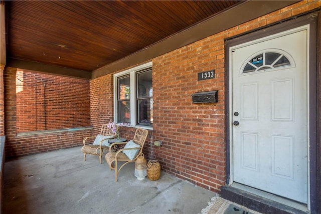 doorway to property featuring brick siding and covered porch