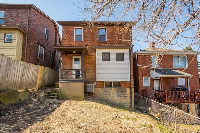 rear view of house with central AC unit, a fenced backyard, and brick siding