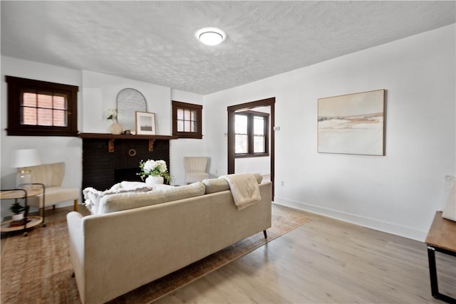 living area with baseboards, a textured ceiling, and wood finished floors