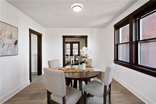 dining space featuring baseboards and wood finished floors