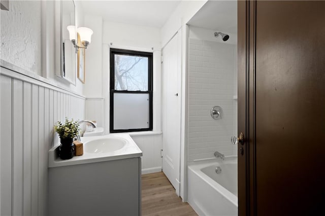 full bathroom featuring wainscoting, washtub / shower combination, vanity, and wood finished floors