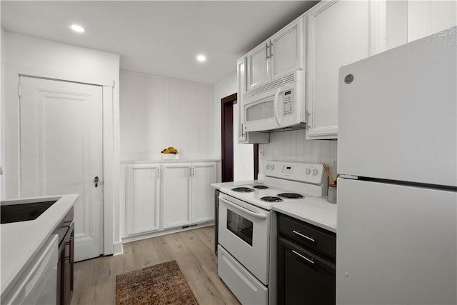 kitchen with light countertops, light wood-style flooring, recessed lighting, white cabinets, and white appliances