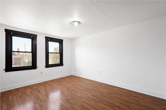 unfurnished room with wood finished floors, baseboards, and a textured ceiling