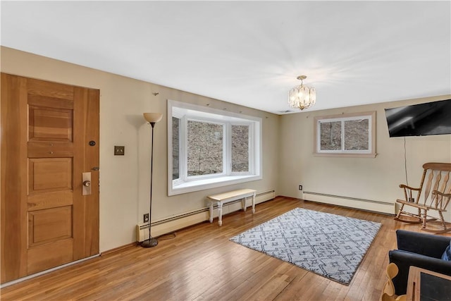 sitting room featuring a chandelier, baseboard heating, and wood finished floors