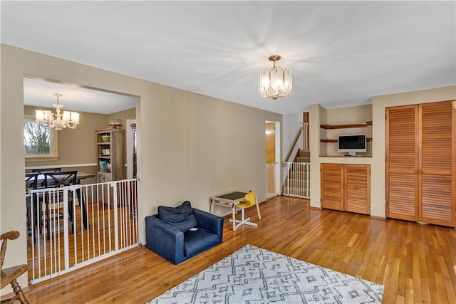 living area featuring stairs, an inviting chandelier, and wood finished floors