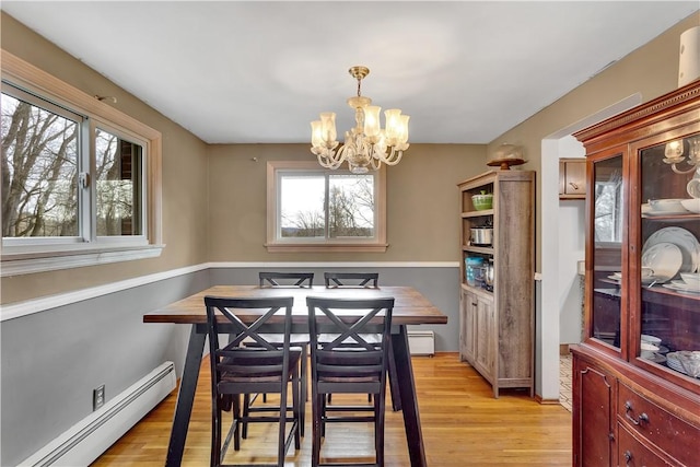 dining space featuring a baseboard heating unit, light wood-style floors, and a chandelier