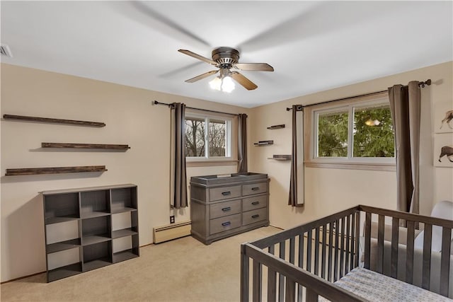 bedroom with light carpet, visible vents, a ceiling fan, and a baseboard radiator