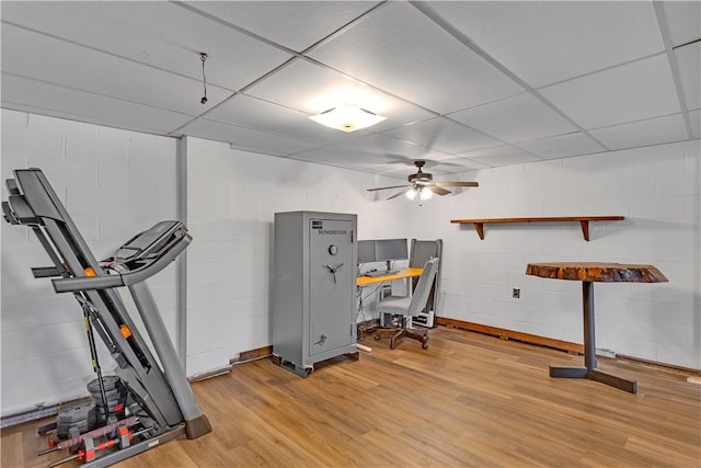 interior space featuring a ceiling fan, concrete block wall, light wood-style floors, and a drop ceiling