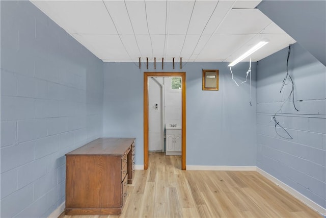 basement with baseboards, concrete block wall, and light wood-style floors