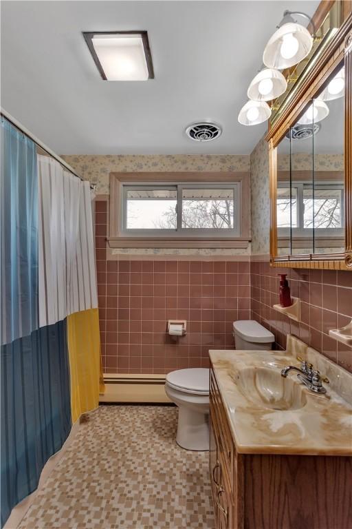 bathroom featuring vanity, visible vents, a baseboard radiator, tile walls, and toilet