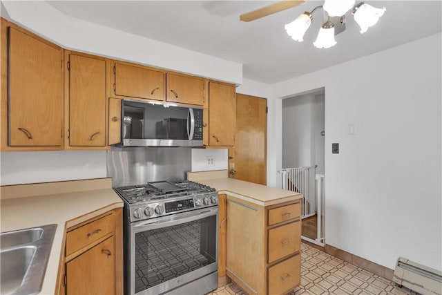 kitchen featuring light countertops, baseboard heating, a peninsula, stainless steel appliances, and a sink