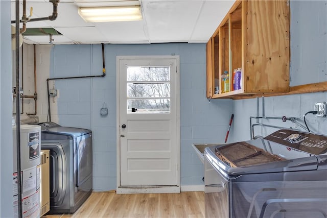 laundry room featuring gas water heater, separate washer and dryer, light wood-style floors, concrete block wall, and laundry area