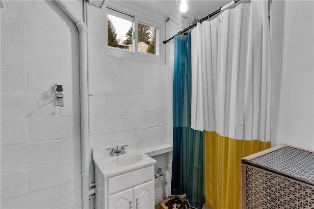 bathroom with vanity, a shower with shower curtain, and concrete block wall