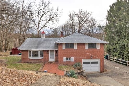 tri-level home with driveway, brick siding, and an attached garage