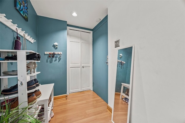 corridor with baseboards and light wood finished floors