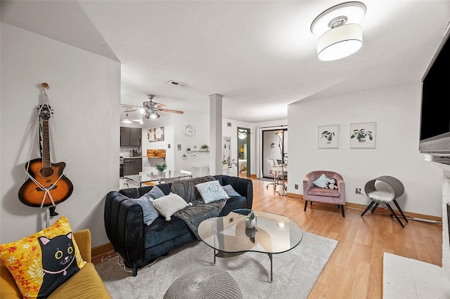 living area featuring light wood-style flooring, baseboards, visible vents, and ceiling fan