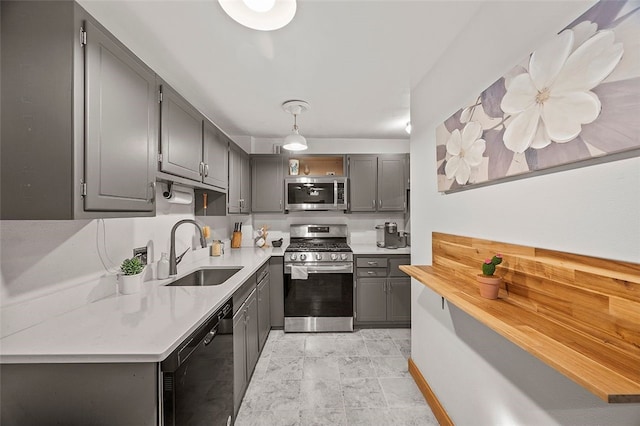 kitchen with light countertops, gray cabinets, appliances with stainless steel finishes, hanging light fixtures, and a sink