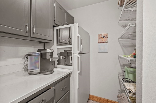 kitchen with light countertops, baseboards, freestanding refrigerator, and gray cabinetry