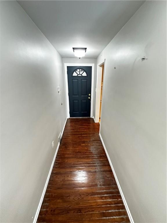 doorway featuring baseboards and hardwood / wood-style floors