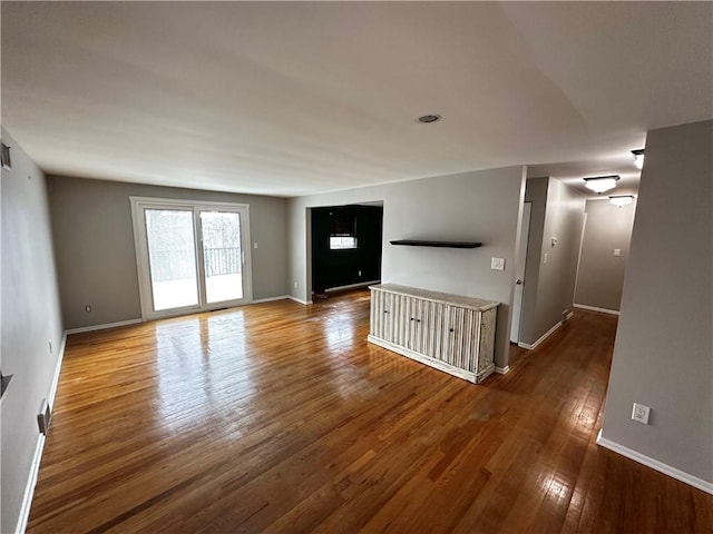 unfurnished living room with dark wood-type flooring and baseboards