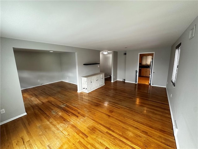 unfurnished living room featuring hardwood / wood-style floors and baseboards