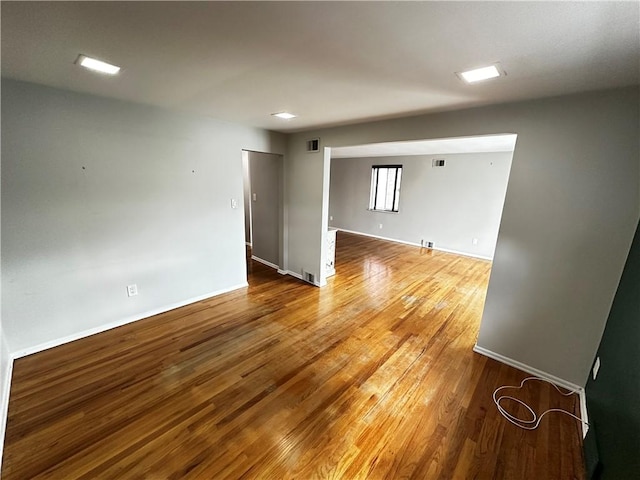 empty room featuring baseboards, visible vents, and wood-type flooring