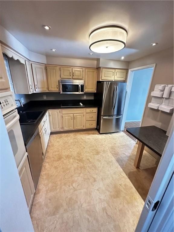 kitchen with dark countertops, recessed lighting, stainless steel appliances, and a sink