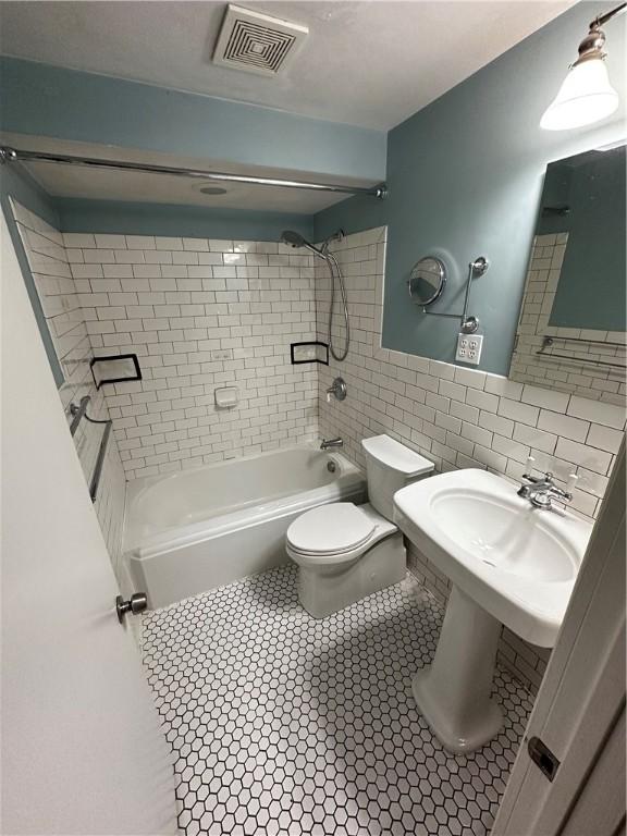 full bathroom with visible vents, toilet, tile walls, tile patterned flooring, and shower / bathtub combination