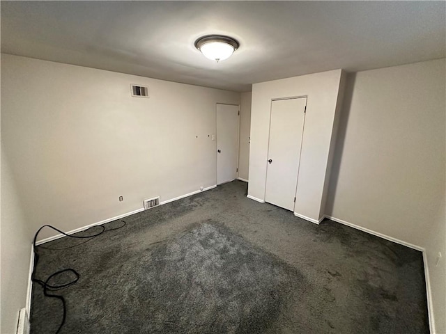 unfurnished bedroom with visible vents, baseboards, and dark colored carpet