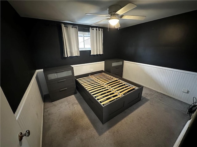 bedroom featuring a wainscoted wall, carpet floors, and ceiling fan