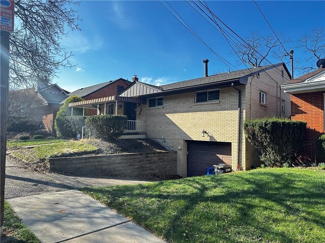 5534 Pocusset St, Squirrel Hill, PA 15217 - view of front facade featuring brick siding, a front yard, driveway, and an attached garage