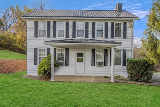 colonial inspired home featuring a front yard, cooling unit, a standing seam roof, a chimney, and metal roof