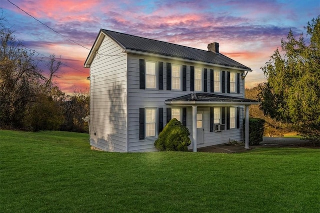 view of front of home with metal roof, a front yard, cooling unit, and a chimney