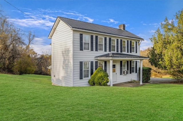 colonial home featuring a front lawn, cooling unit, metal roof, and a chimney