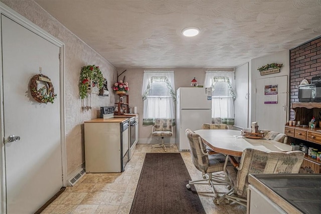 kitchen with baseboards, electric range, washer / clothes dryer, freestanding refrigerator, and a textured ceiling