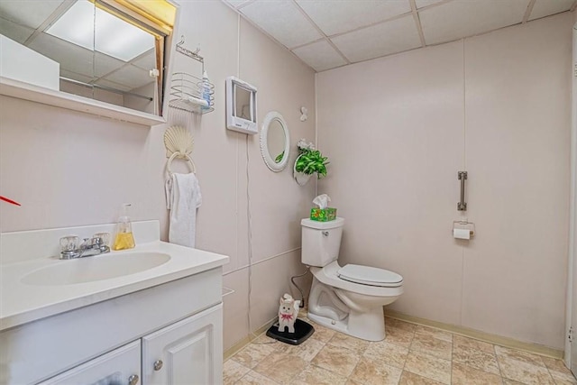 bathroom with a paneled ceiling, toilet, and vanity