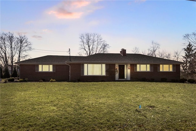 ranch-style home with brick siding, a lawn, and a chimney