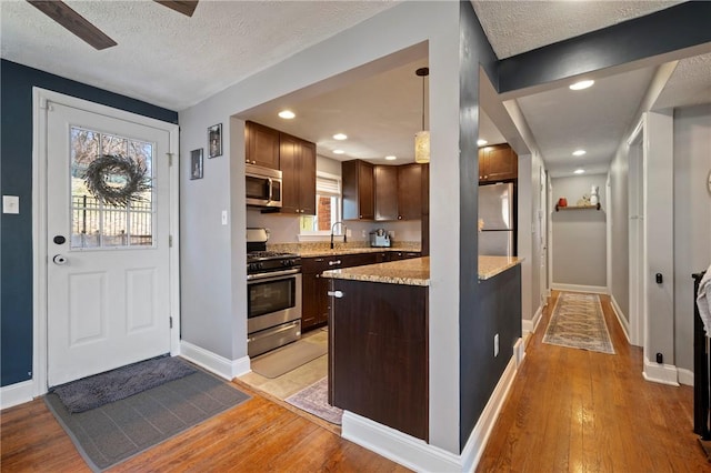 kitchen featuring a textured ceiling, light wood-style floors, appliances with stainless steel finishes, and a sink