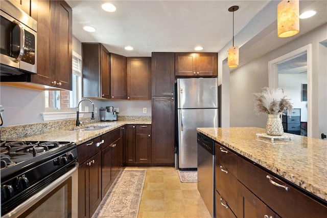 kitchen with a sink, light stone counters, stainless steel appliances, dark brown cabinetry, and hanging light fixtures