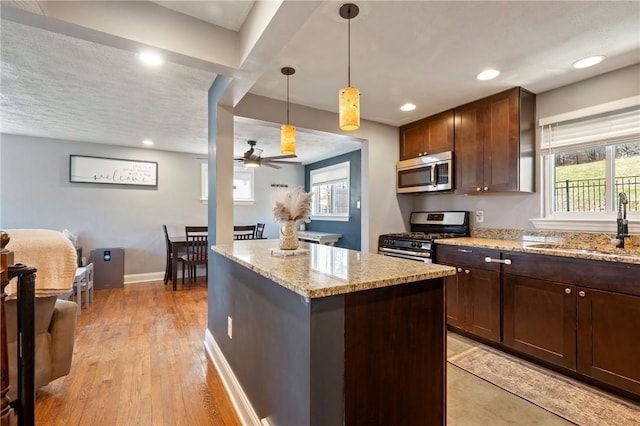 kitchen featuring light stone counters, plenty of natural light, appliances with stainless steel finishes, and a sink