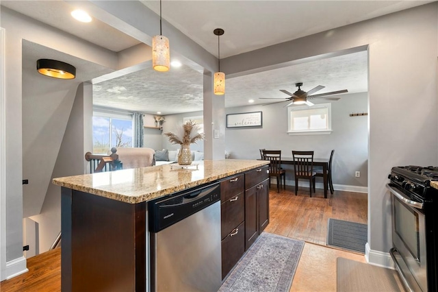 kitchen featuring light wood finished floors, light stone counters, dark brown cabinets, and appliances with stainless steel finishes